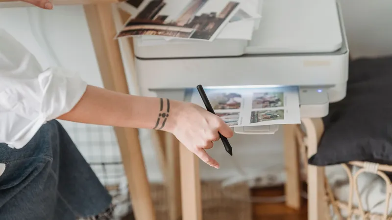 Person am Drucker mit Ausdrucken